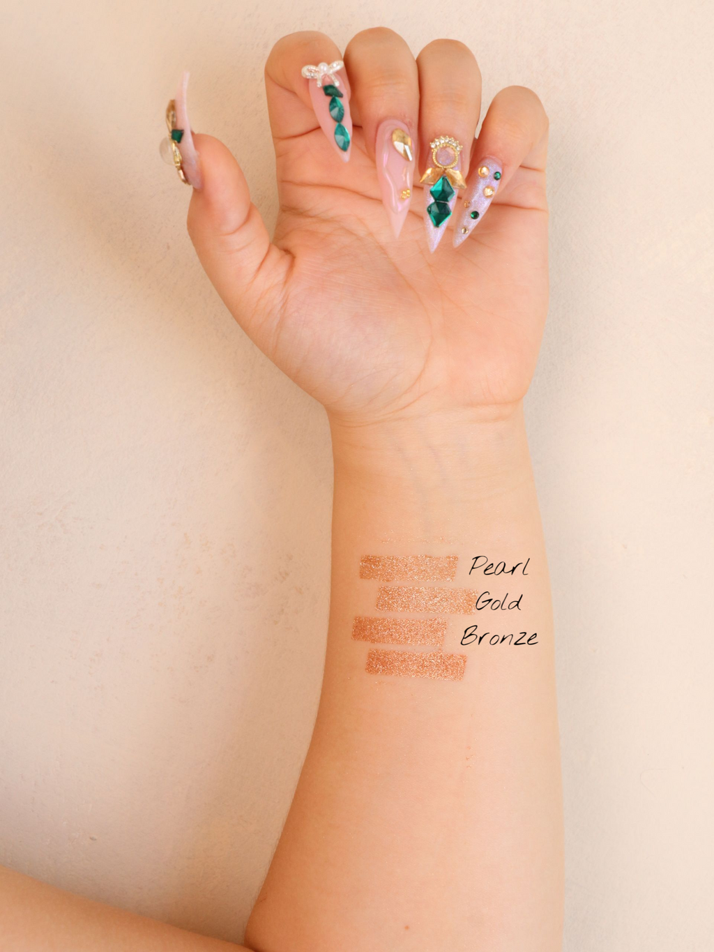 Hand with decorative nail art and cosmetic swatches on wrist