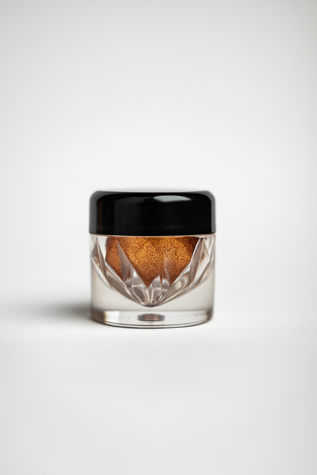 Small glass jar with black lid containing a brown substance on a white background
