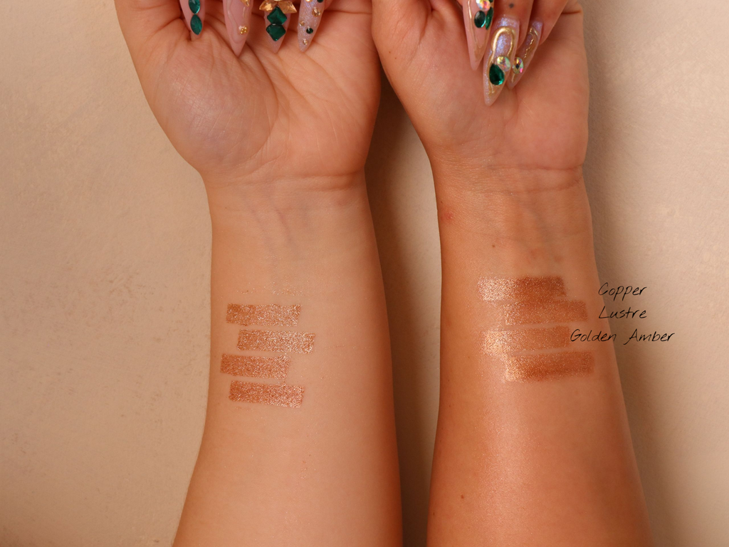 Swatches of makeup on a two person's wrists against a beige background