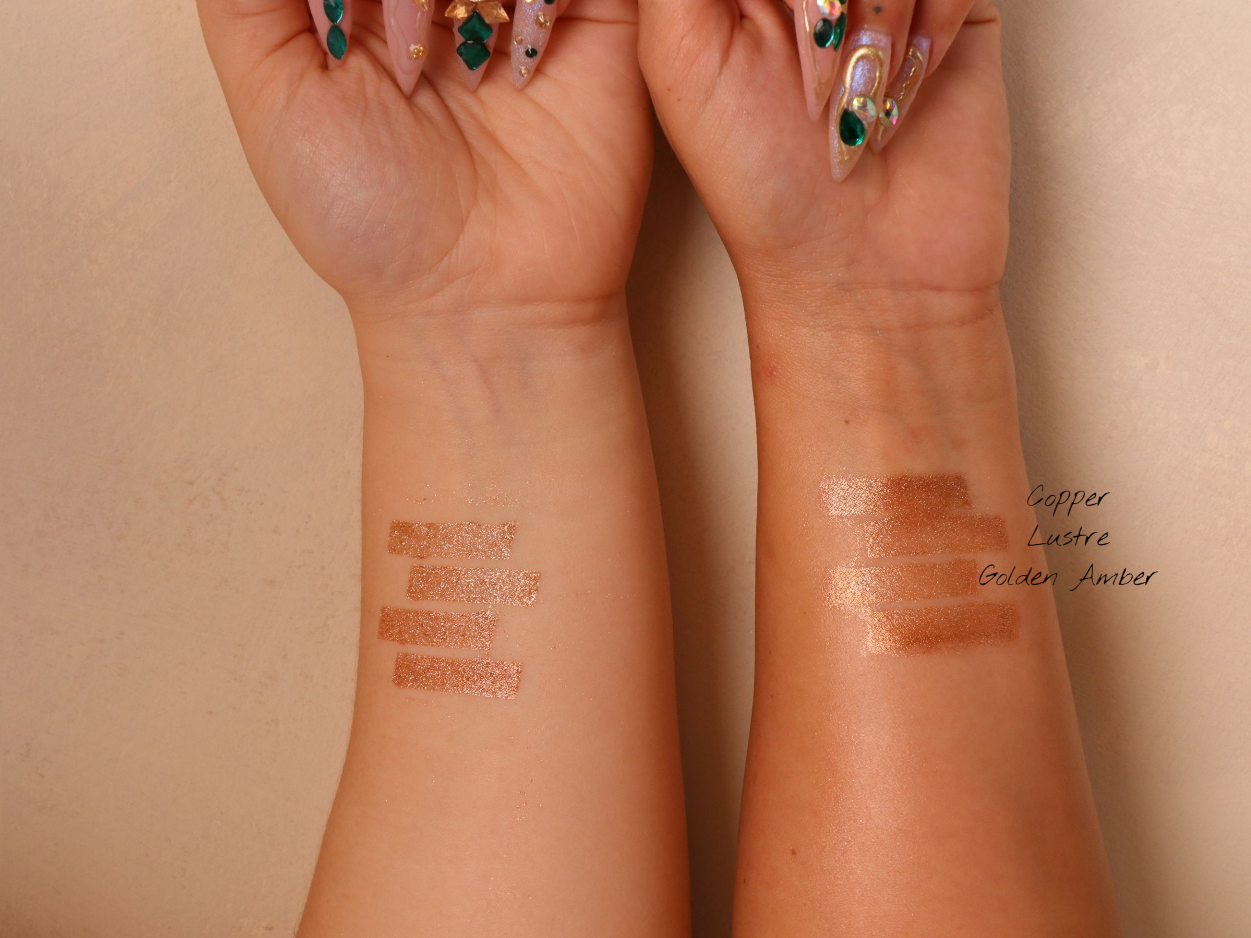 Swatches of makeup on a two person's wrists against a beige background