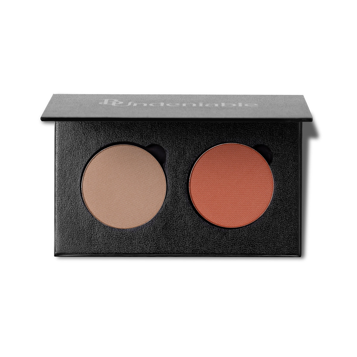 An open black makeup palette with two round pressed powder pans, one light beige and one warm terracotta orange, on a white background. The brand name 'B:Undeniable' is printed on the lid.