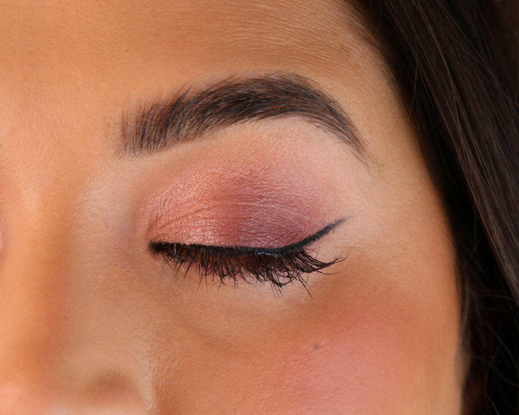 Close-up of a person's eye with pink eyeshadow and eyeliner.
