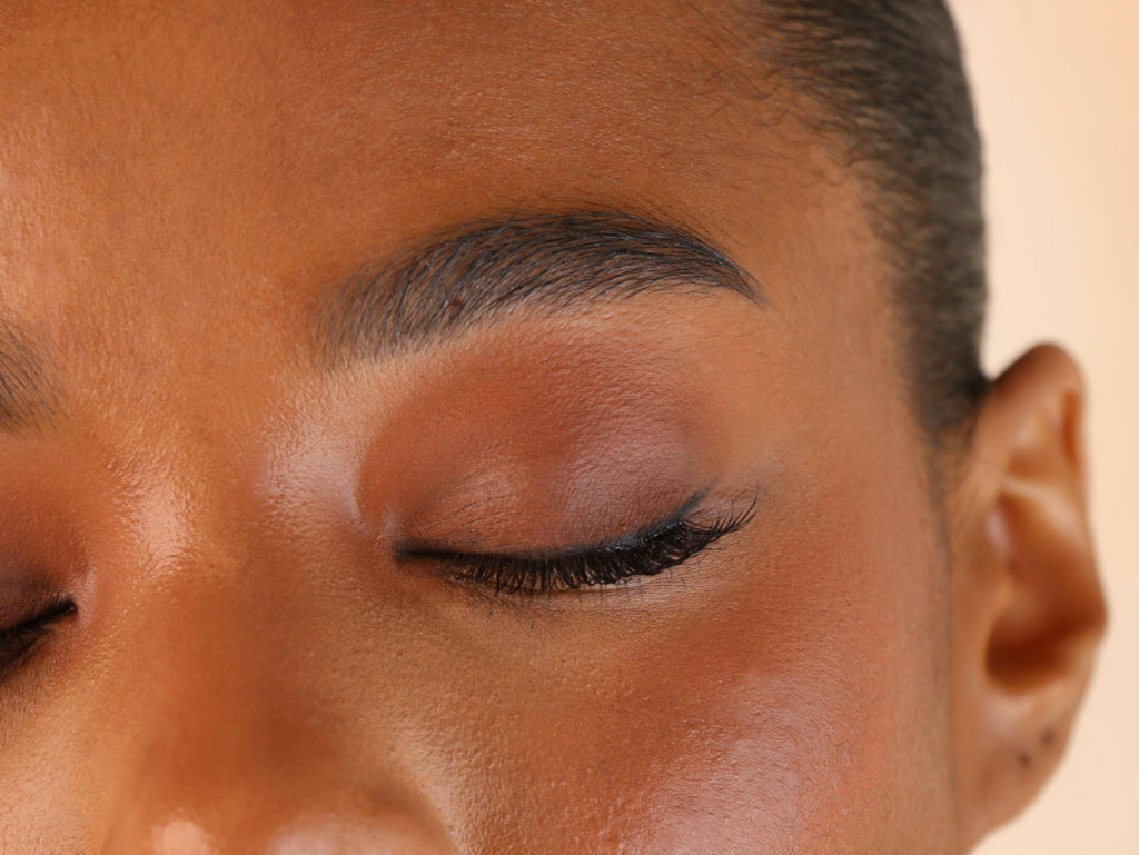 Close-up of a person's eye with eyelashes on a beige background