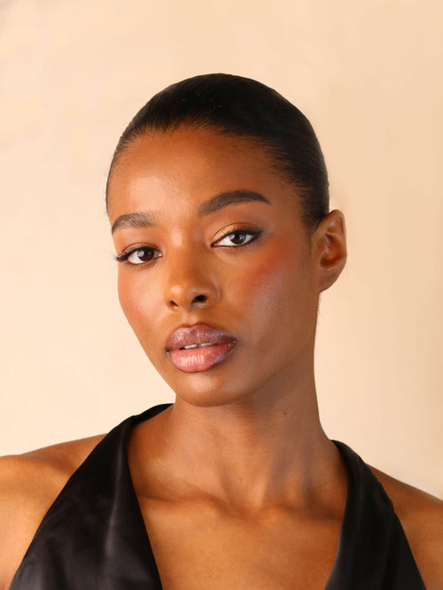 Woman wearing a black halter top against a beige background